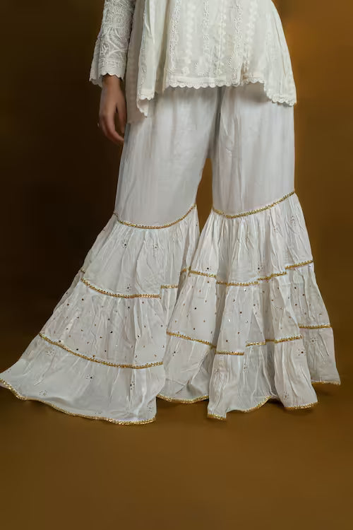White tiered  Chikankari pants with gold trim on a brown background