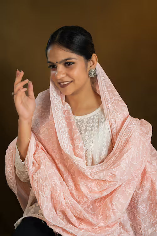 Woman wearing a pink dupatta over her shoulder against a brown background
