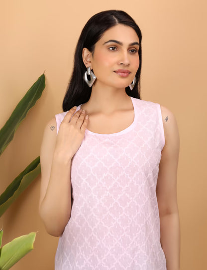 Woman wearing a light pink Chikankari sleeveless top with a subtle pattern against a beige background