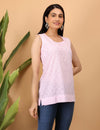 Woman wearing a light pink Chikankari sleeveless top with a subtle pattern against a beige background