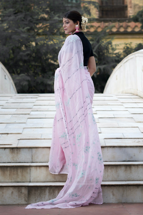 Woman in a pink saree standing on stone steps with a blurred background