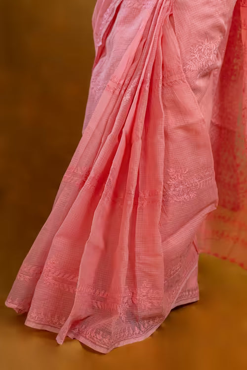 Close-up of a pink saree with intricate patterns on a brown background