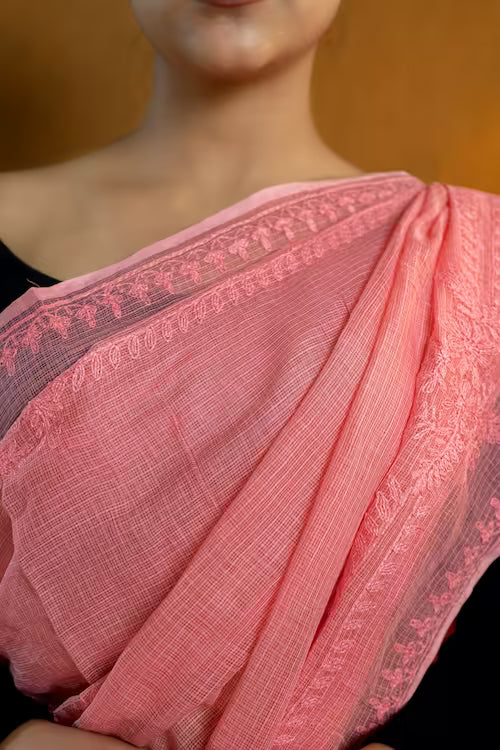 Close-up of a pink saree with intricate patterns on a blurred background