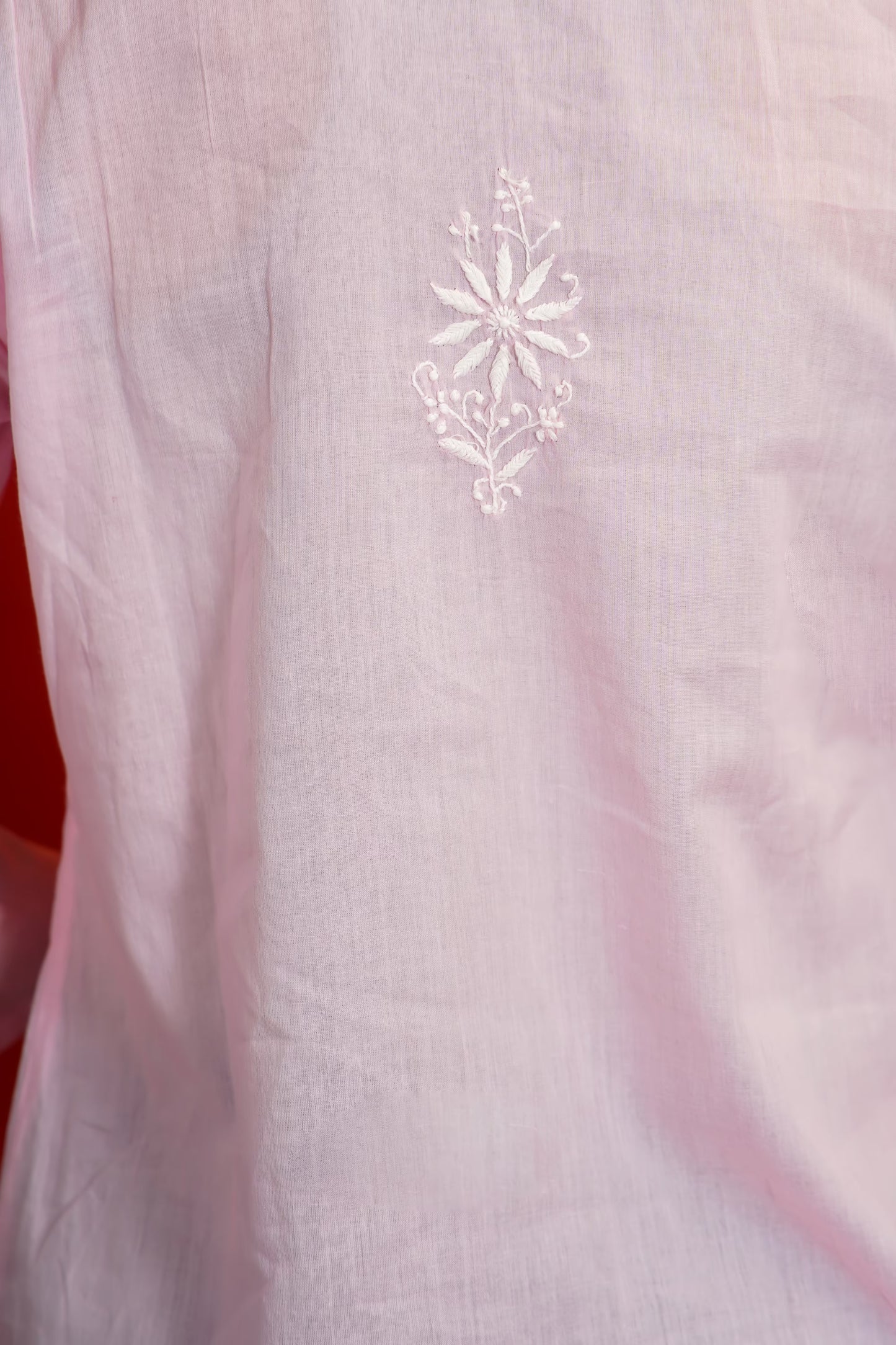 White embroidered design on a light pink fabric background