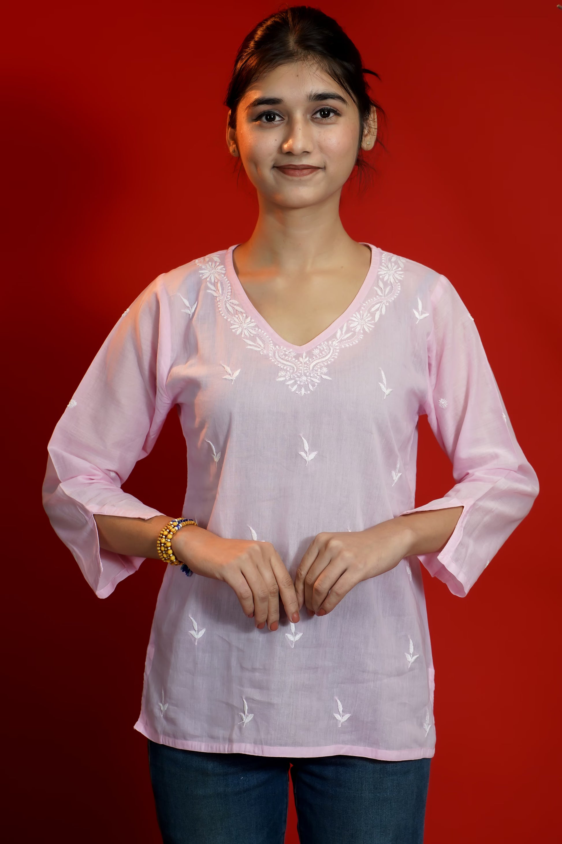 Woman wearing a light pink blouse with white patterns on a red background