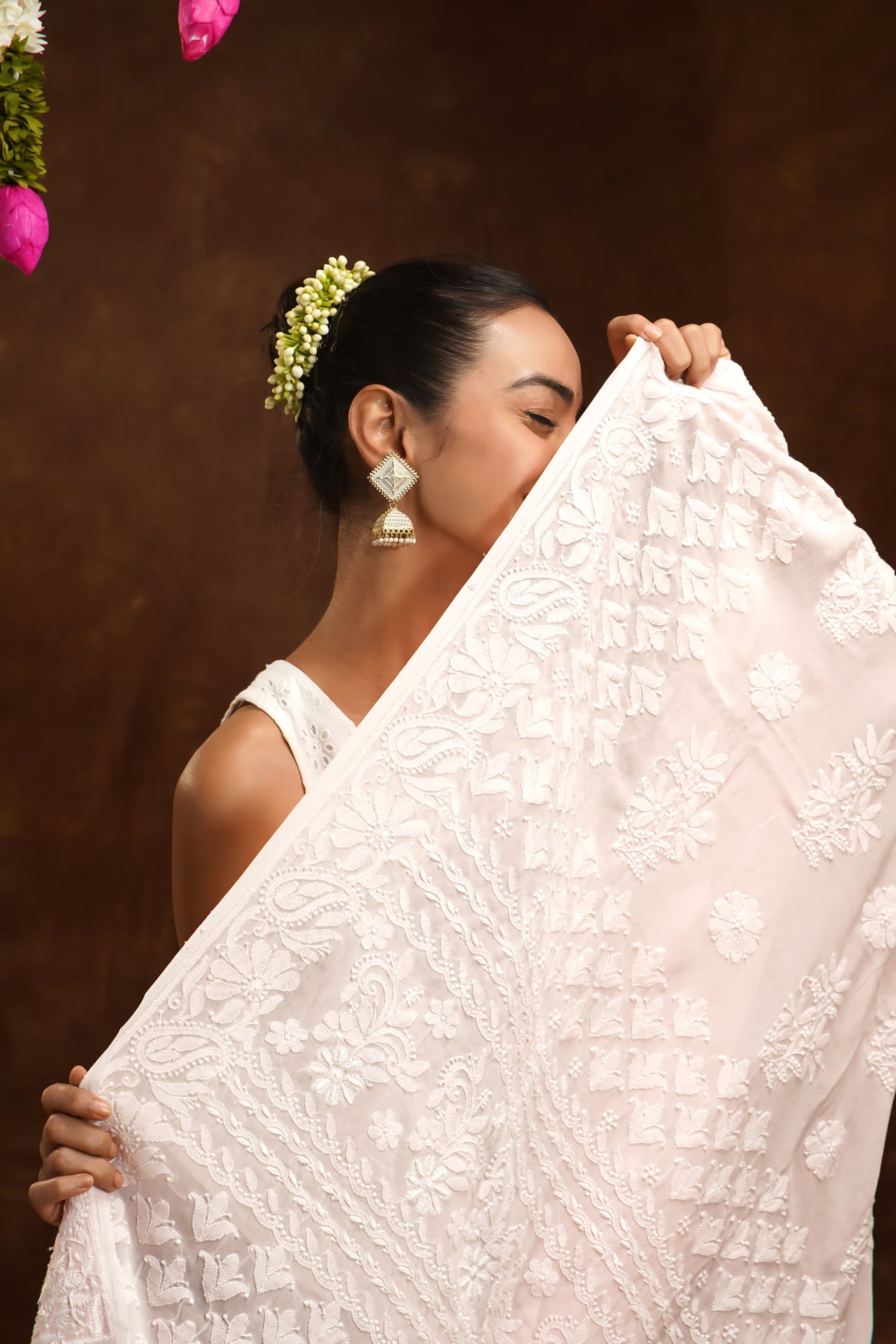 Woman holding a white embroidered fabric against a brown background