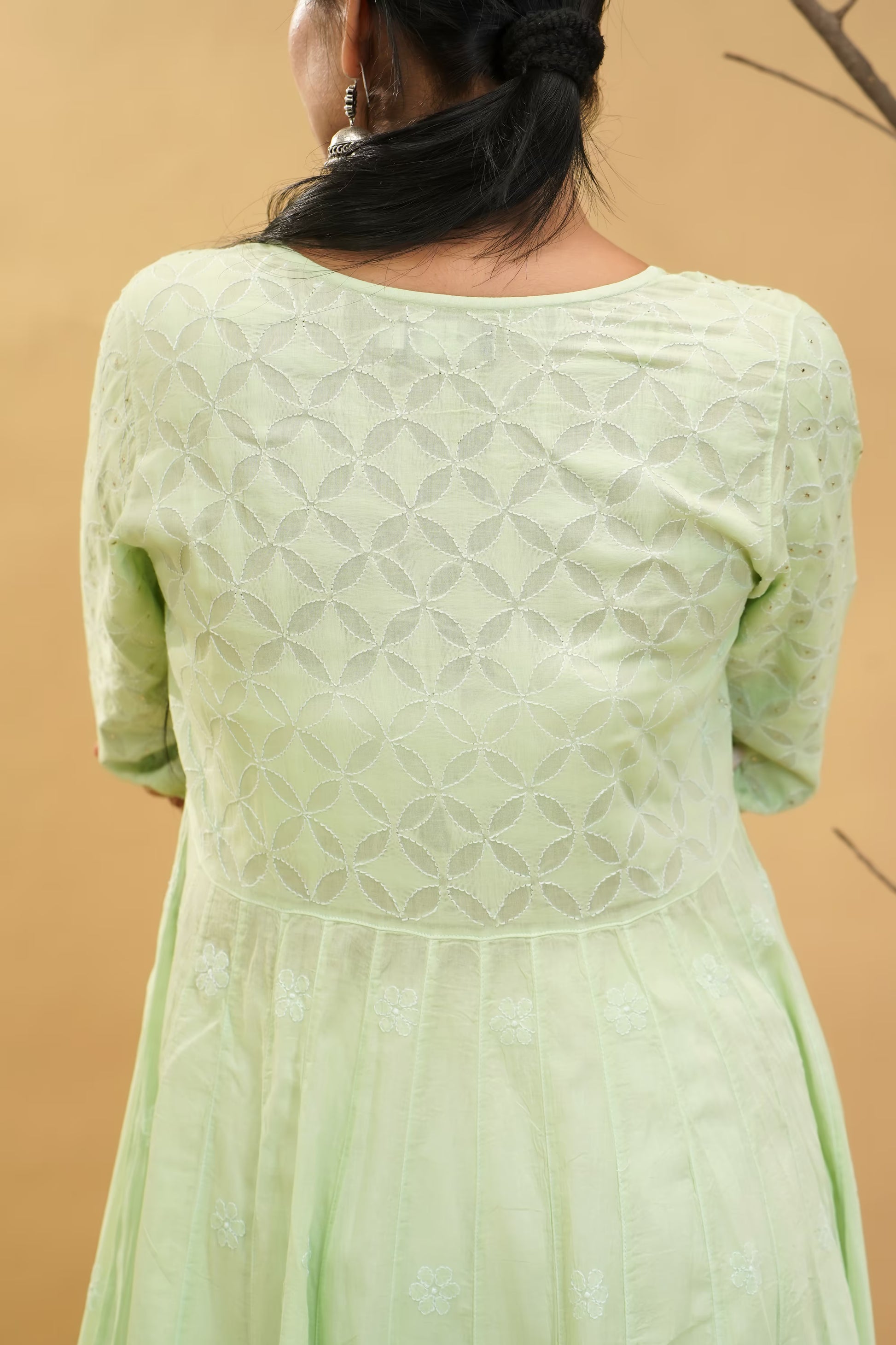 Pista green dress with intricate patterns on a beige background