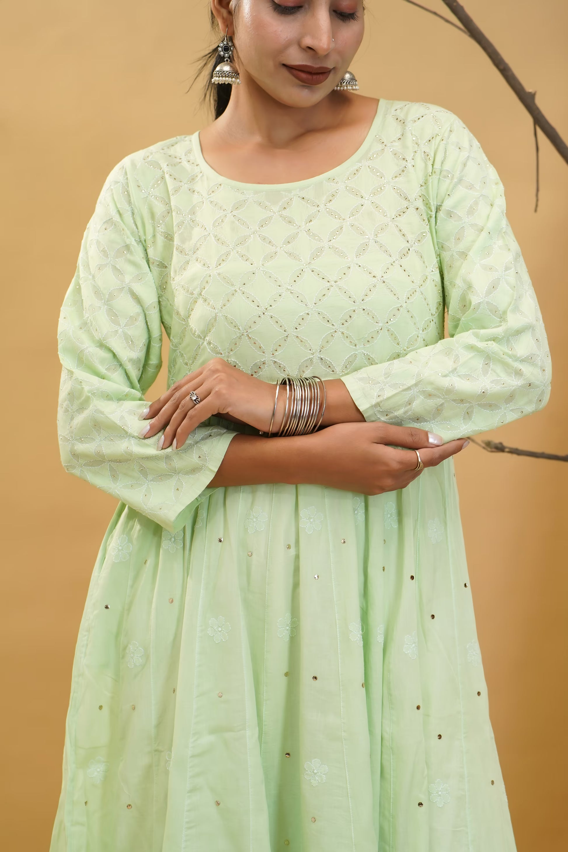 Woman wearing a pista green dress with a textured pattern against a beige background