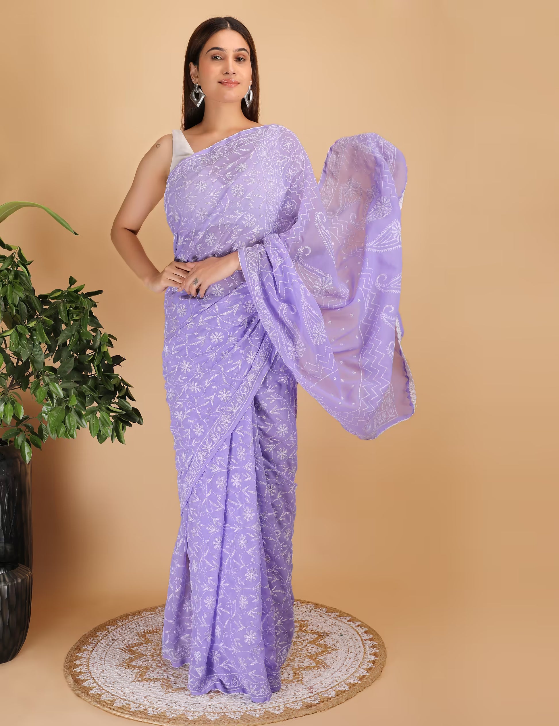 Woman wearing a purple saree with a white  Chikankari pattern on a beige background