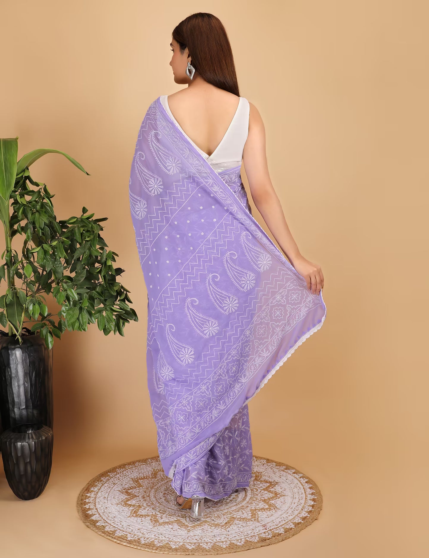 Woman wearing a purple saree with white  Chikankari patterns on a beige background