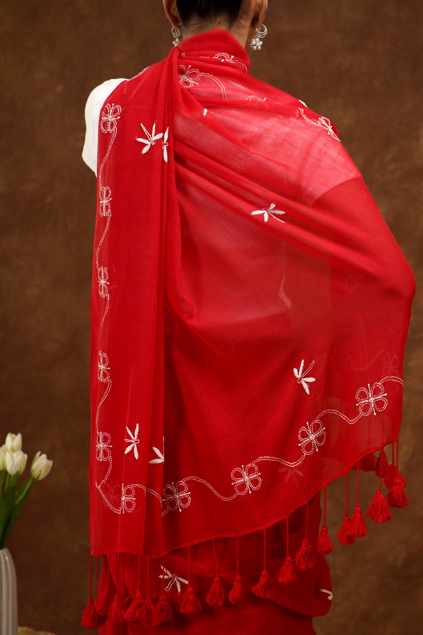 Red Saree with white patterns and tassels on a brown background