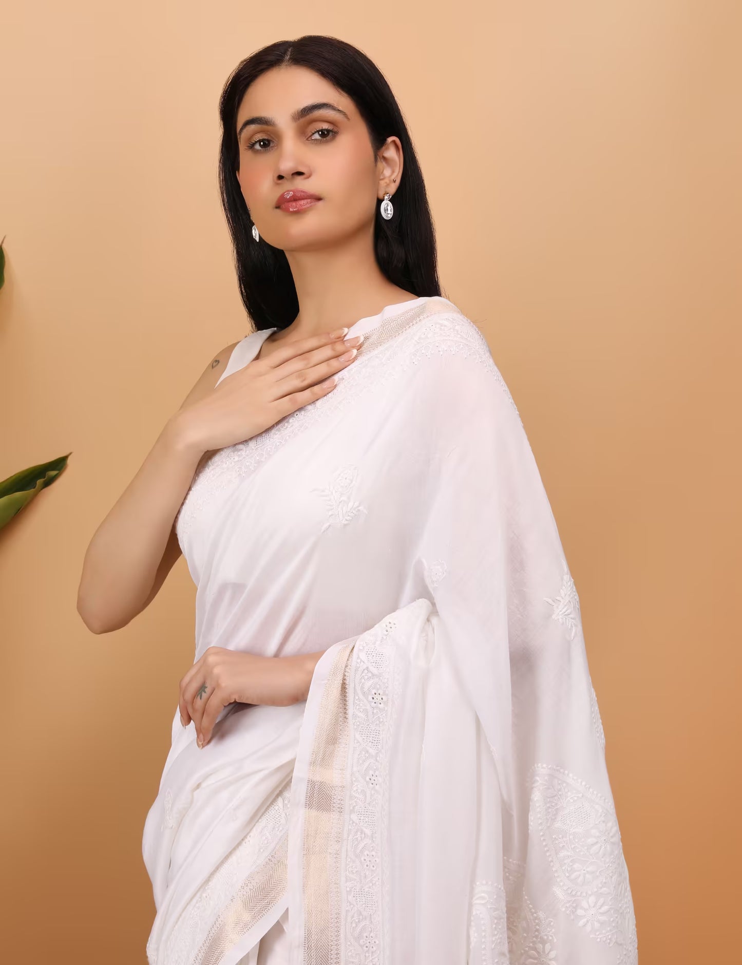 Woman wearing a white saree against a beige background