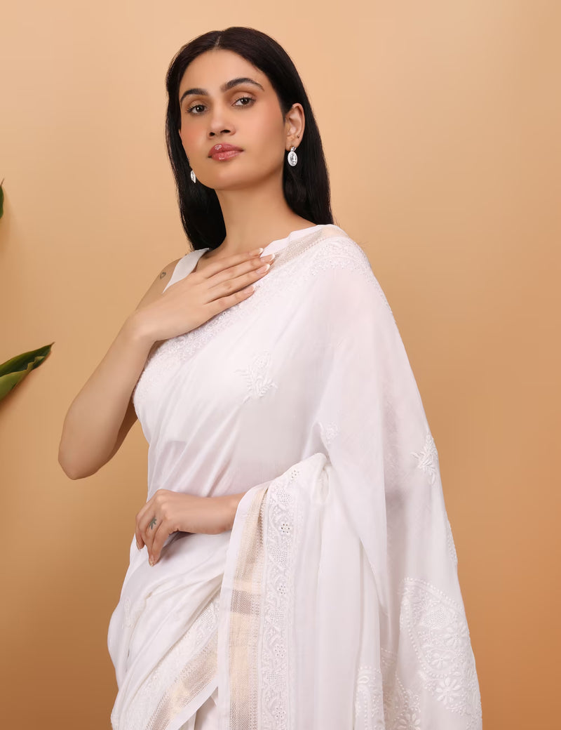 Woman wearing a white saree against a beige background