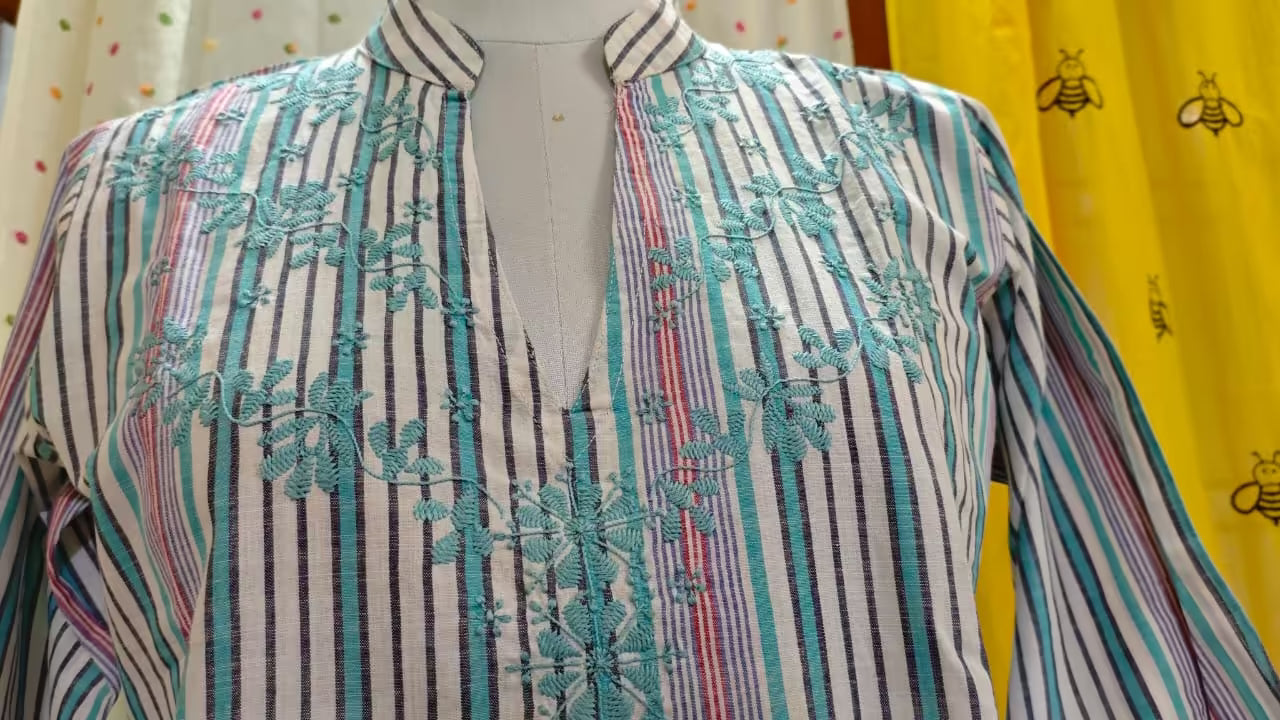 Striped shirt with Chikankari  embroidery on a mannequin against a yellow background with bee designs.