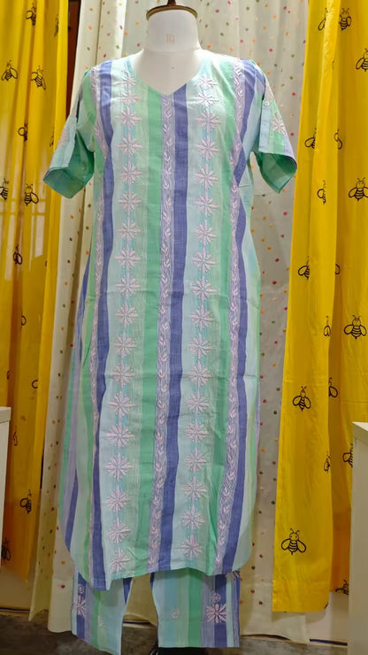 Mannequin wearing a  Chikankari patterned dress with yellow curtains in the background