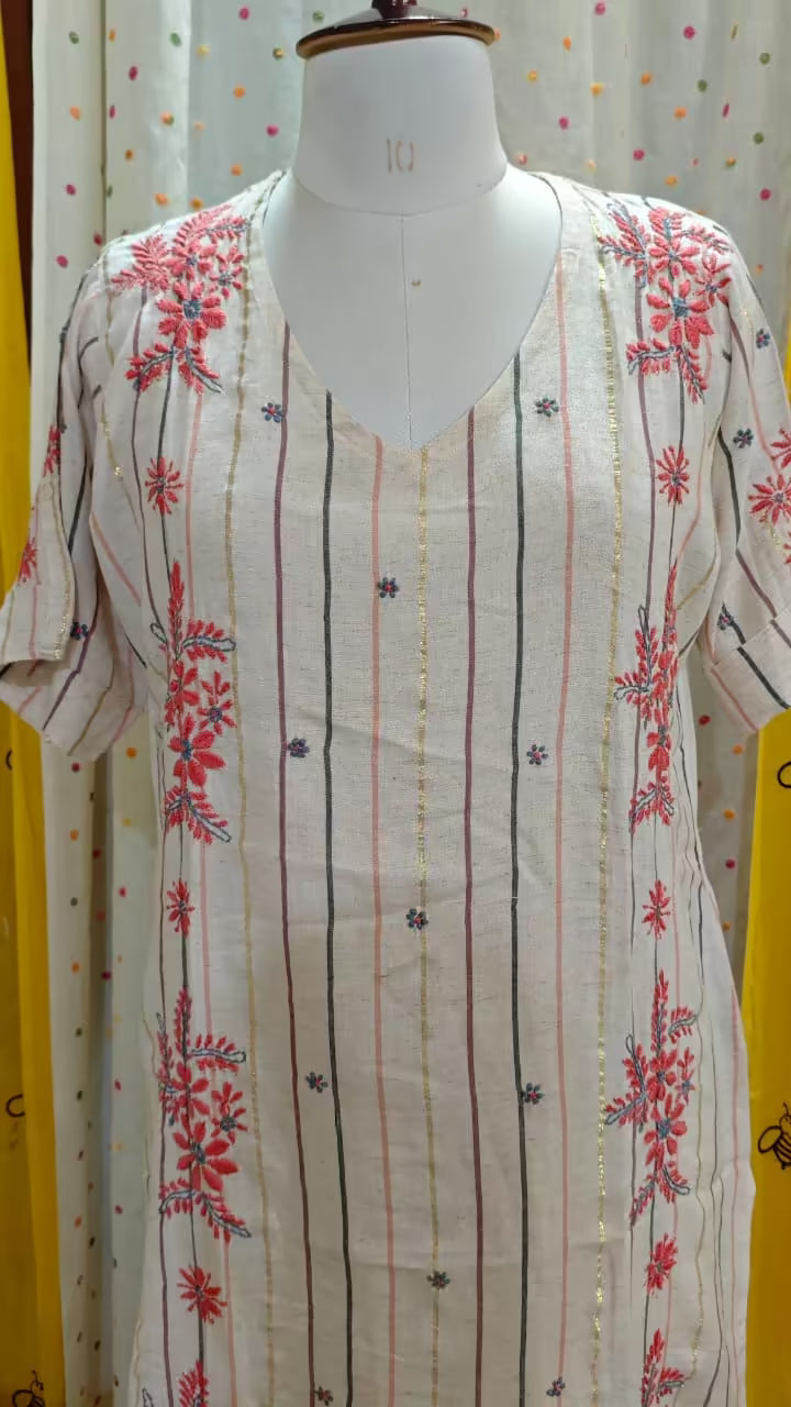 White Chikankari  kurta with red  patterns on a mannequin against a polka dot curtain background