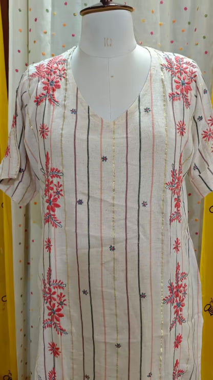 White Chikankari  kurta with red  patterns on a mannequin against a polka dot curtain background