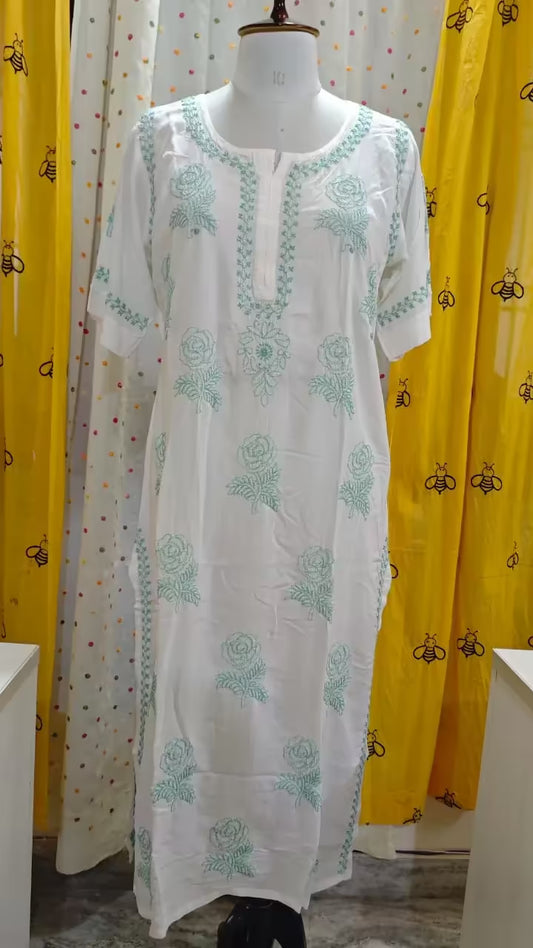White Hand embroidered Chikankari  kurta on a mannequin with yellow curtains in the background
