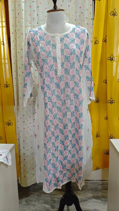 Long patterned  Chikankari dress on a mannequin against a colorful curtain background