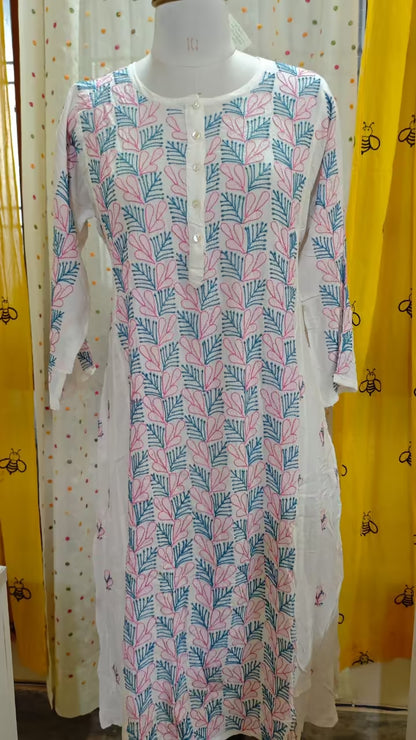 Long Chikankari dress on a mannequin with colorful curtains in the background