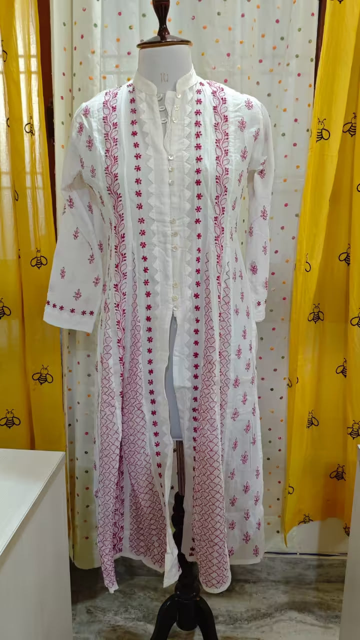 White embroidered  Chikankari dress on a mannequin with yellow curtains in the background