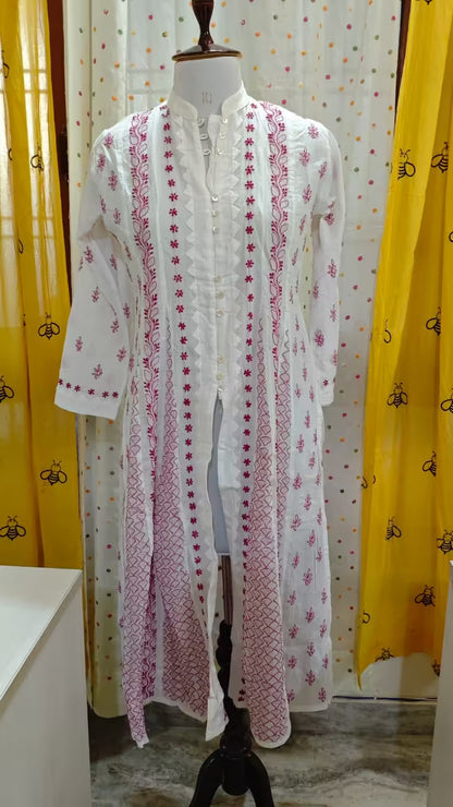 White embroidered  Chikankari dress on a mannequin with yellow curtains in the background