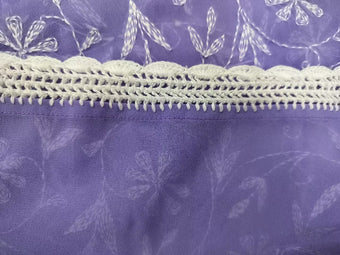 Close-up of a purple fabric with white Crochia  patterns.