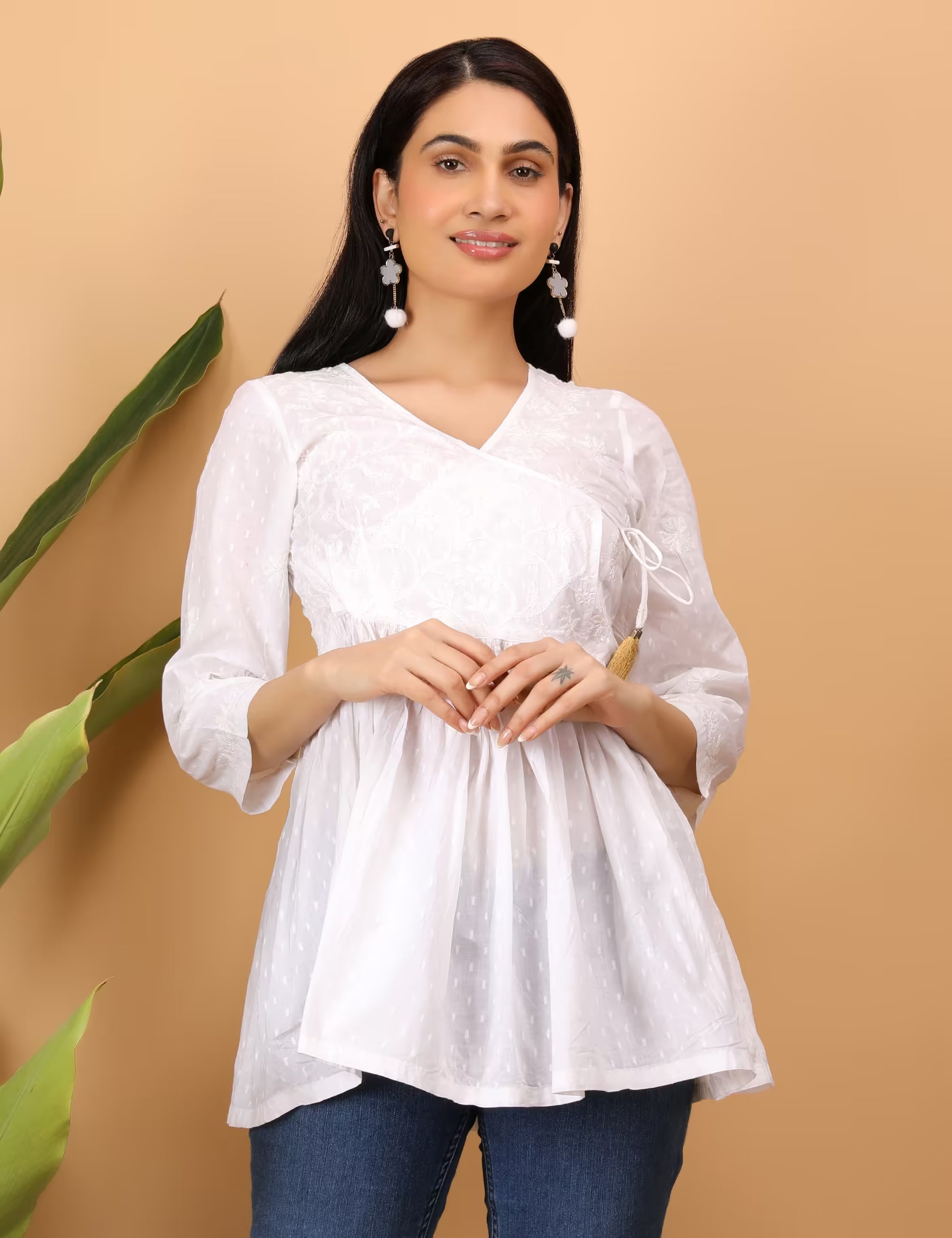 Woman wearing a white hand embroidered chikankari top with a beige background
