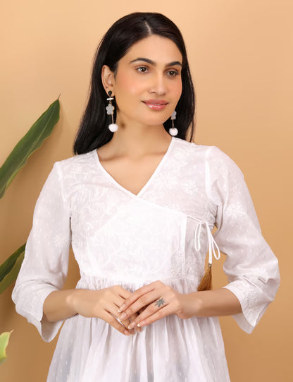 Woman wearing a white chikankari top  with a beige background