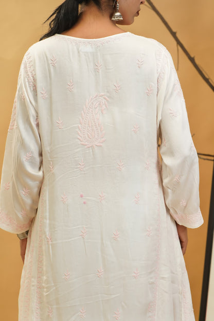White embroidered dress worn by a person against a beige background