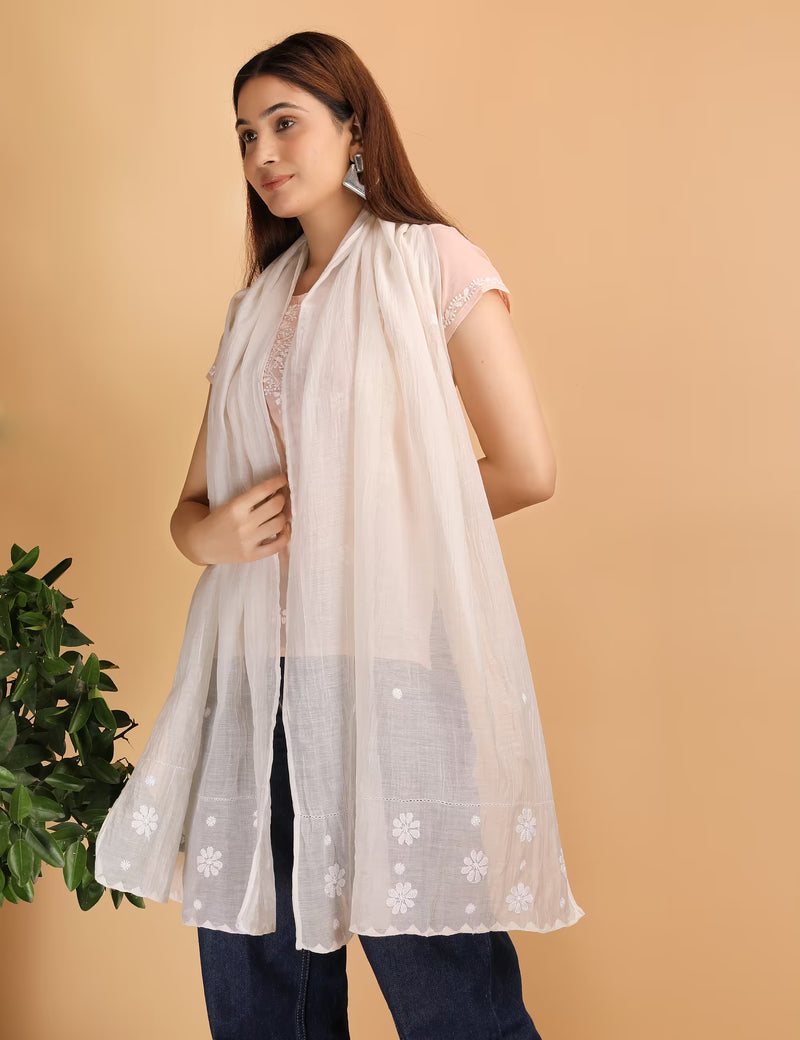 Woman wearing a beige embroidered scarf against a beige background