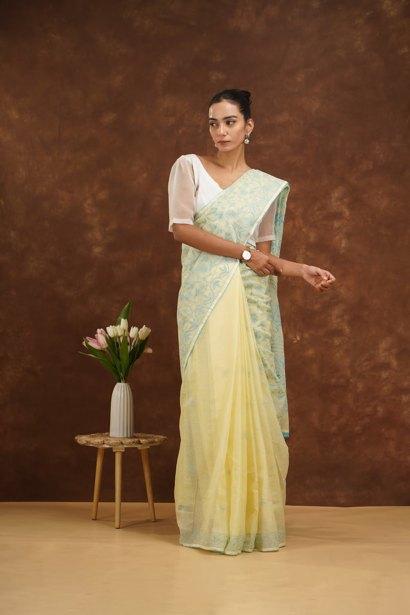 Woman in a light yellow saree with a brown background