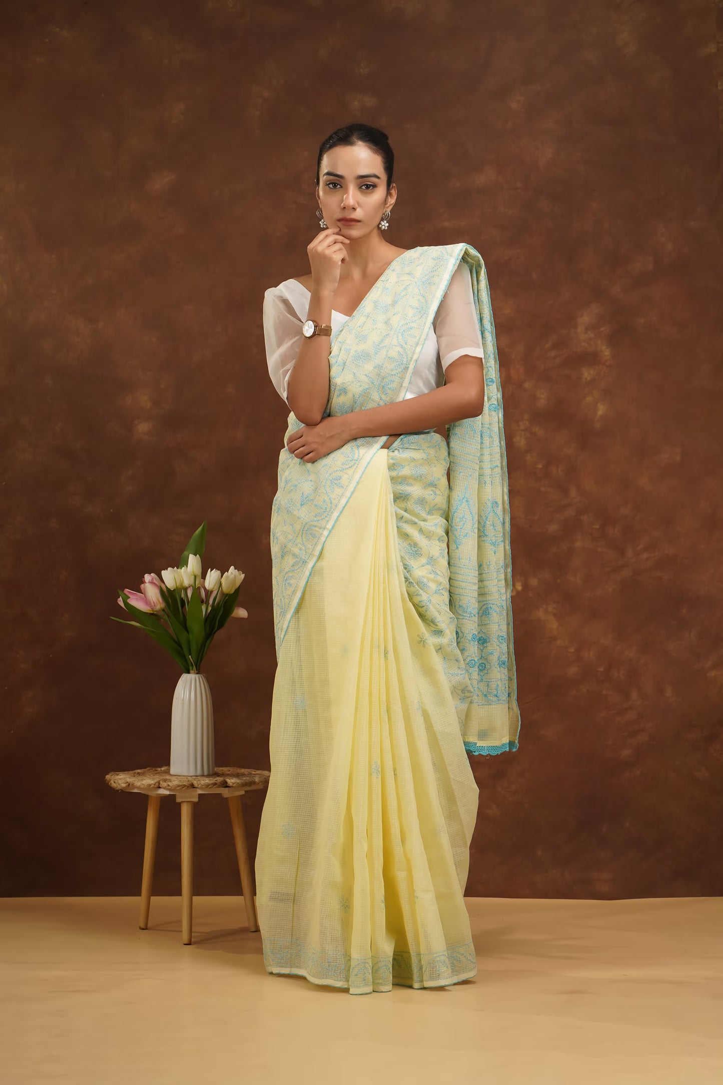 Woman wearing a yellow and blue saree with a brown background