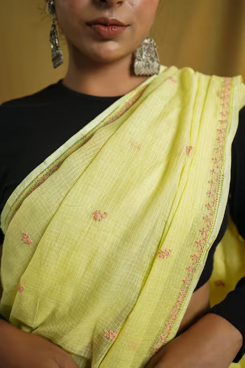 Woman wearing a light yellow  saree with peach Chikankari patterns on a blurred background
