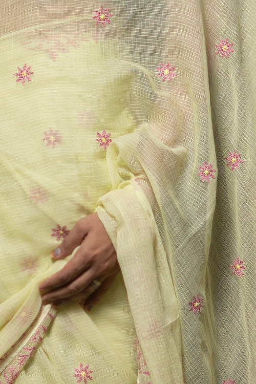 Light yellow fabric with pink floral embroidery held by a hand