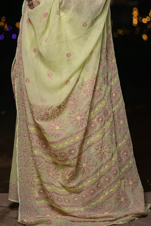 Light green saree with pink floral patterns on a dark background