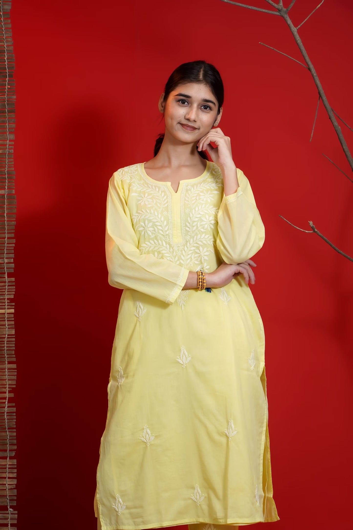 Woman wearing a yellow embroidered dress against a red background