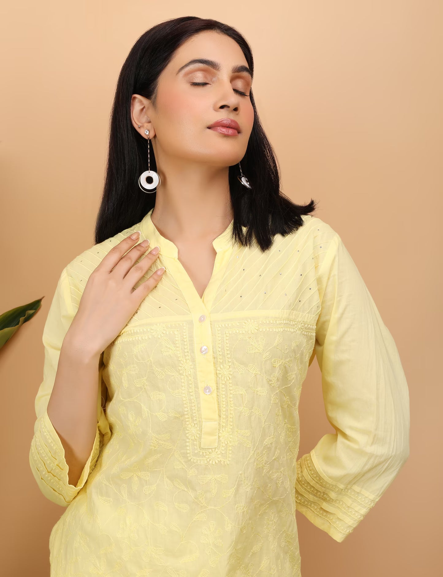 Woman wearing a light yellow kurta against a beige background