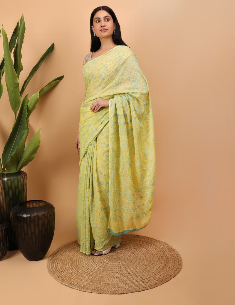 Woman wearing a yellow saree with a Chikankari pattern against a beige background