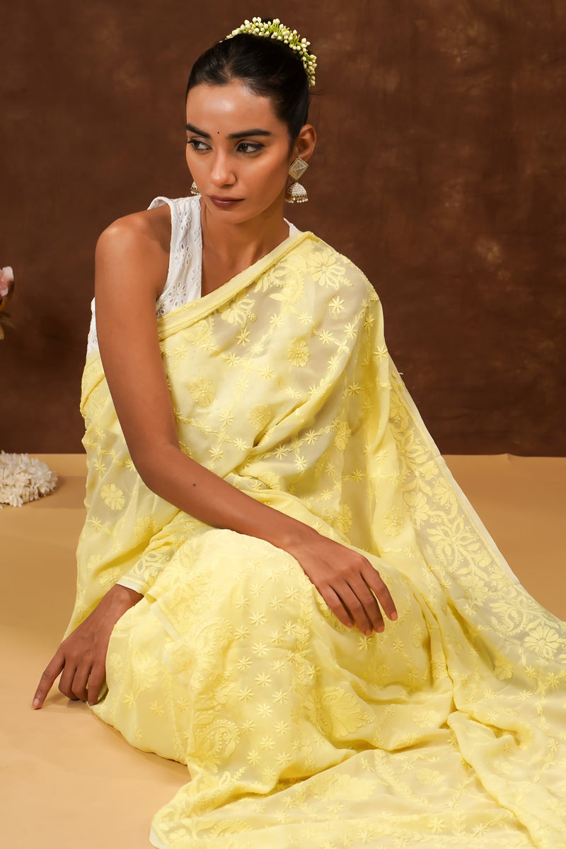 Woman in a yellow saree sitting on a brown background